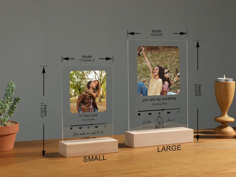 Puede incluir: Dos marcos de fotos de acr&iacute;lico con base de madera. El marco m&aacute;s peque&ntilde;o mide 11 cm de ancho y 17,5 cm de alto. El marco m&aacute;s grande mide 15 cm de ancho y 23 cm de alto. Ambos marcos tienen una foto de dos personas y un gr&aacute;fico de reproductor de m&uacute;sica con t&iacute;tulos de canciones y nombres de artistas. El marco m&aacute;s peque&ntilde;o tiene la canci&oacute;n "In Your Love" de Tyler Childers. El marco m&aacute;s grande tiene la canci&oacute;n "You Are My Sunshine" de Christina Perri.