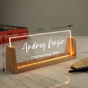 May include: A wooden desk nameplate with a clear acrylic insert that lights up. The name "Andrey Nazir" and the title "Chief Technology Officer" are engraved on the acrylic insert. The nameplate measures 8.3 inches wide and 3.4 inches high.