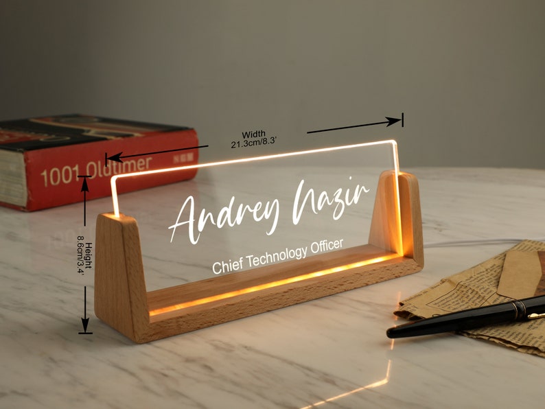 May include: A wooden desk nameplate with a clear acrylic insert that lights up. The name "Andrey Nazir" and the title "Chief Technology Officer" are engraved on the acrylic insert. The nameplate measures 8.3 inches wide and 3.4 inches high.