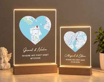 May include: Two rectangular acrylic light panels with wooden bases. Each features a heart-shaped map with a red location pin, names, the text WHERE WE FIRST MEET, and a date. One displays San Francisco, the other New York City.