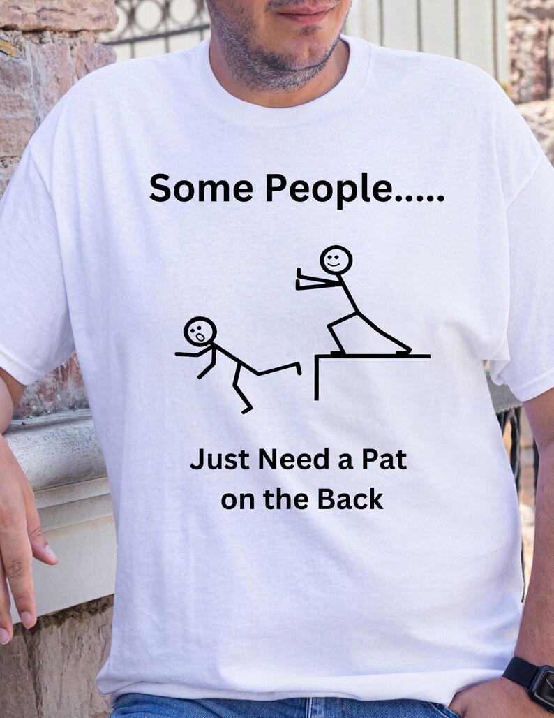 May include: White t-shirt with a black stick figure design. The text on the shirt reads "Some People.... Just Need a Pat on the Back".