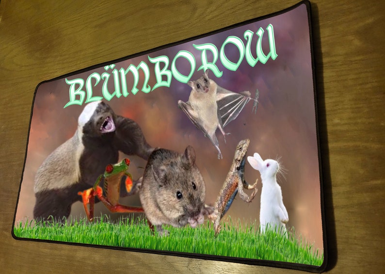 Pu&ograve; includere: Un tappetino per mouse colorato con il testo "Bl&uuml;mBorow" in lettere verdi. Il tappetino per mouse presenta una variet&agrave; di animali, tra cui un tasso del miele, una rana, un topo, un pipistrello, una lucertola e un coniglio.