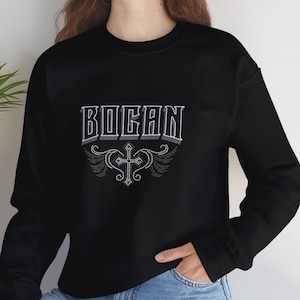 May include: Black sweatshirt with long sleeves and a white graphic design that says "BOGAN" with a cross and wings.