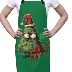 May include: Green Christmas apron with a cartoon Christmas tree wearing a Santa hat and the text "Merry Crisis".