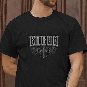 May include: A black t-shirt with a white graphic design that says "BOGAN" with a cross and wings.