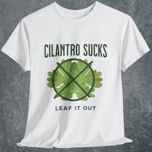 May include: White t-shirt with the text "CILANTRO SUCKS" in green, above a green graphic of cilantro crossed out with a green "X". Below the graphic is the text "LEAF IT OUT".