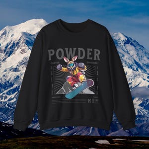 Könnte beinhalten: Schwarzes Sweatshirt mit einem Grafikdruck eines Schneebrett fahrenden Kaninchens. Die Grafik enthält den Text "POWDER" und die Wörter "CARVER" und "SHREDDER" auf beiden Seiten des Kaninchens.