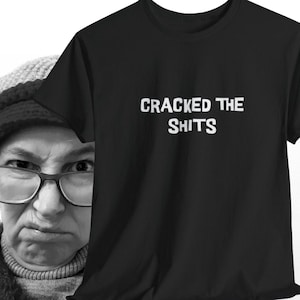 Peut inclure: T-shirt noir avec du texte blanc qui dit "Cracked the Shits".