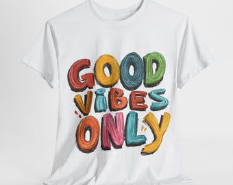 May include: White t-shirt with the phrase "GOOD VIBES ONLY" in colorful, bubble-style letters. The text is in red, orange, yellow, blue, green, and pink. The shirt is made of a soft material.