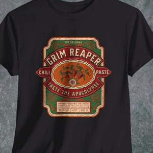 May include: A black t-shirt with a vintage-style label design featuring the text "The Original Grim Reaper Chili Paste" and the tagline "Taste the Apocalypse". The label is green, red, and orange with a drawing of red chilli peppers.