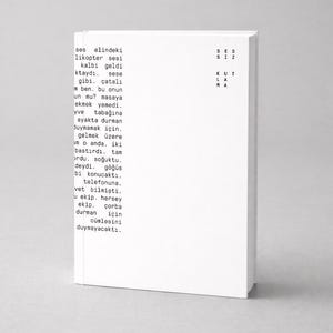 May include: A white book with black text on the cover and spine. The text is in a foreign language. The book is standing upright on a neutral surface.