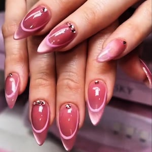 Puede incluir: Una taza de cerámica blanca con un asa negra y el texto "But First, Coffee" en negrita negra. La taza está sobre una superficie de madera. La taza mide aproximadamente 10 cm de altura.