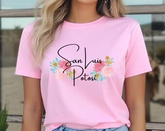 May include: Pink t-shirt with a black graphic that says "San Luis Potosi" with floral accents.