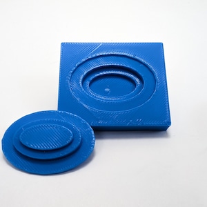 Pu&ograve; includere: Uno stampo in plastica blu stampato in 3D per la creazione di gioielli in resina. Lo stampo &egrave; in due pezzi, una base quadrata e un top ovale separato. Lo stampo ha tre forme ovali concentriche.