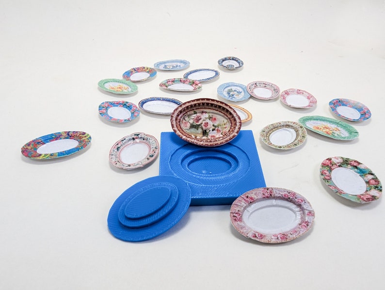 Pu&ograve; includere: Uno stampo in silicone blu per realizzare piccoli piatti ovali, con una variet&agrave; di piatti decorati che lo circondano. Lo stampo &egrave; aperto e un piatto &egrave; posto all'interno.