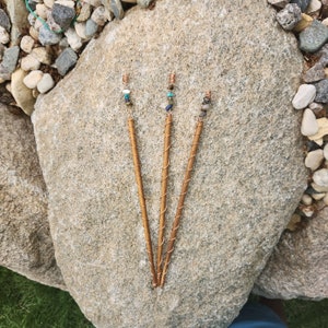 May include: Three copper hair sticks with colorful beads. The sticks are twisted and have a gold finish.