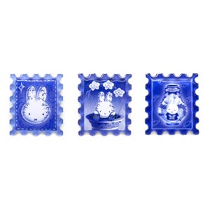 Pu&ograve; includere: Tre francobolli decorativi blu e bianchi con un design a coniglietto dei cartoni animati. Un francobollo mostra un coniglio con una stella, un altro mostra un coniglio in un vaso con fiori e l'ultimo mostra un coniglio in un vaso.