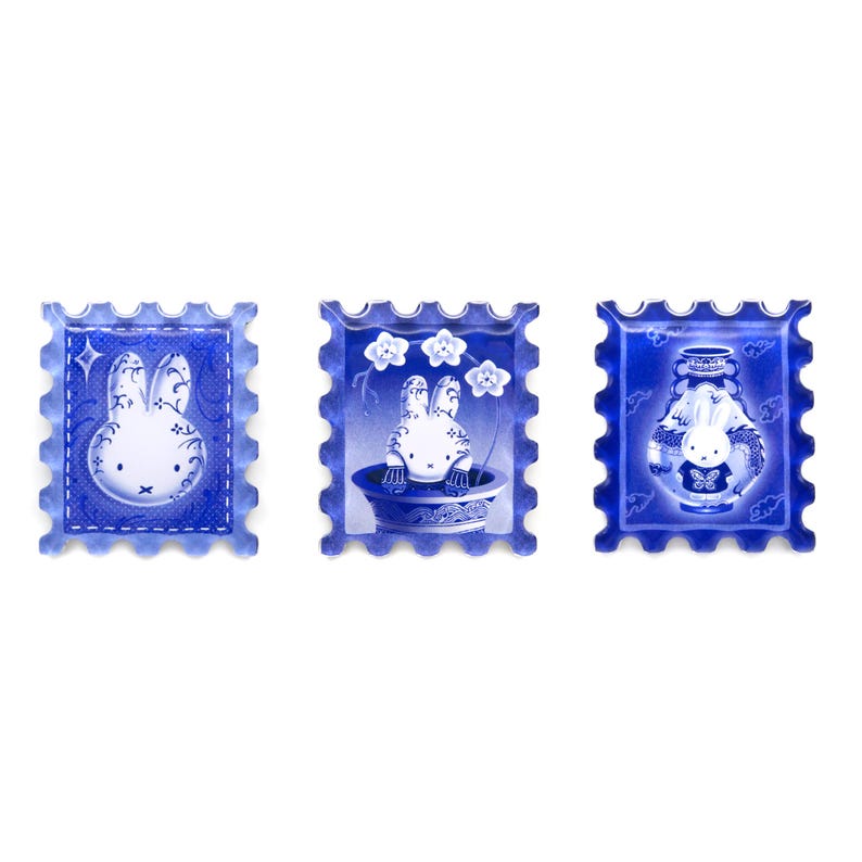 Pu&ograve; includere: Tre francobolli decorativi blu e bianchi con un design a coniglietto dei cartoni animati. Un francobollo mostra un coniglio con una stella, un altro mostra un coniglio in un vaso con fiori e l'ultimo mostra un coniglio in un vaso.