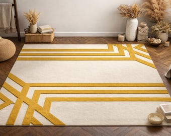 May include: Cream-colored rectangular rug with a geometric design in yellow. The rug features a series of horizontal lines and angular shapes, creating a modern and stylish look. The rug is placed on a wooden floor.