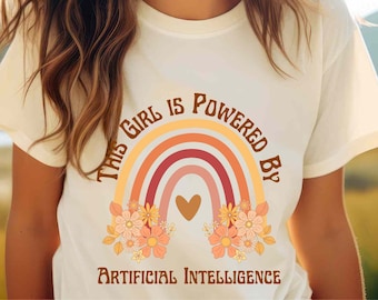 May include: A cream-colored short-sleeve t-shirt featuring a graphic print of a rainbow with a heart in the center, surrounded by flowers. The text reads, This Girl Is Powered By Artificial Intelligence, in a brown, retro-style font.