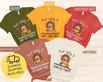 May include: A collection of five t-shirts in various colors, each featuring a turkey graphic with the phrase "Most Likely to" and a different Thanksgiving-themed statement. Colors include olive, gold, heather red, heather clay, and natural.