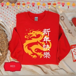 May include: Red sweatshirt with a yellow dragon graphic and the Chinese characters "新年快乐" (Happy New Year) in white.
