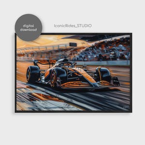 Op de afbeelding: Een ingelijste digitale download print van een Formule 1 raceauto in beweging. De auto is zwart en oranje en scheurt over een circuit met een vage achtergrond van toeschouwers en een heldere lucht. De print is gelabeld met "IconicRides_STUDIO" en "digitale download".