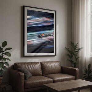 May include: Framed abstract art print of a Formula 1 race car in motion. The artwork features a blurred effect with streaks of red, orange, and blue against a dark background. The car is in the center, with a black frame.