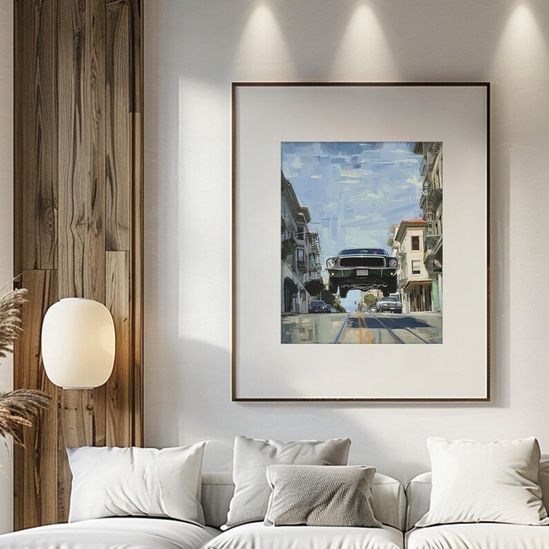 Op de afbeelding: Een ingelijst schilderij van een groene auto die over een stadsstraat vliegt. De auto is een klassieke muscle car met een zwart interieur en een wit kenteken. De stadsstraat is omzoomd met gebouwen en er zijn bomen op de achtergrond.