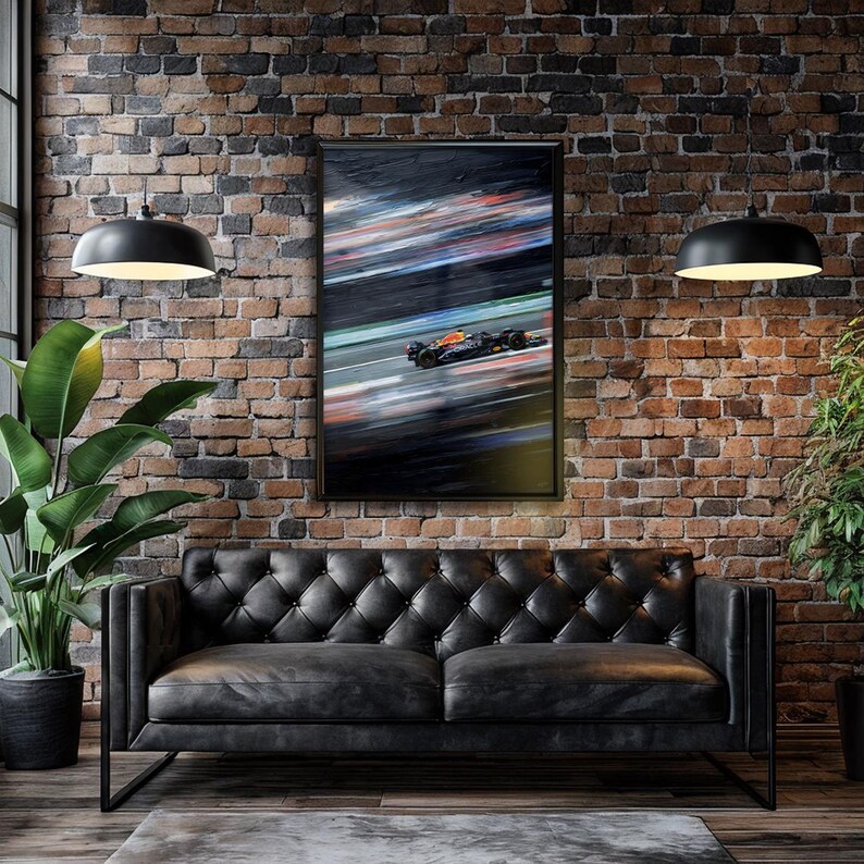 May include: Framed print of a Formula 1 race car in motion, with blurred streaks of color. The artwork is displayed on a brick wall above a black leather sofa. Two black pendant lights hang from the ceiling, and a large potted plant is on the left.