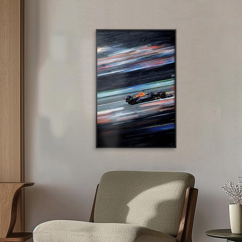 May include: A framed abstract painting of a Formula 1 race car in motion. The artwork features a blurred background with streaks of red, white, and blue, suggesting speed. The car is black and orange, positioned on a gray track.