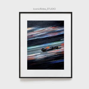 May include: Framed artwork of a Formula 1 race car speeding on a track. The car is black, orange, and blue, with the Oracle logo visible. The background features blurred streaks of color, suggesting speed. The text "IconicRides_STUDIO" is at the top.