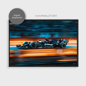 Op de afbeelding: Een zwarte en groene Formule 1-raceauto met nummer 44 aan de zijkant, die met oranje en blauwe wazige lichten over een circuit racet. De auto heeft het woord "PETRONAS" aan de zijkant.