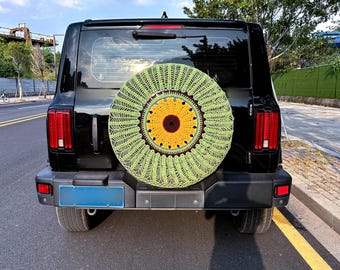May include: A black SUV with a green and yellow crocheted sunflower spare tire cover.