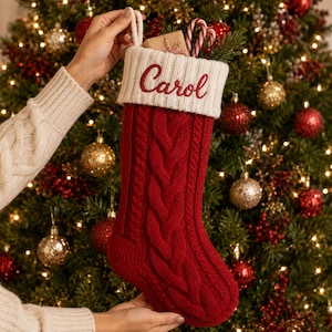 Peut inclure: Une chaussette de Noël en tricot torsadé rouge profond avec un revers crème brodé du prénom Carol en lettres rouges. La chaussette comporte une boucle de suspension assortie et une petite boîte cadeau glissée à l'intérieur.