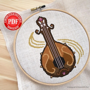 Op de afbeelding: Cross stitch patroon PDF-download voor een bruine en gouden luit met een paarse edelsteen bovenop. De luit is omgeven door drie gouden lijnen.