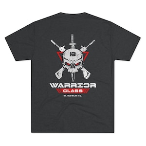 Puede incluir: Camiseta gris oscuro con un gráfico de calavera blanca y rifles cruzados. La calavera tiene ojos rojos y un triángulo blanco con la letra "B" en su interior. El texto "Warrior Class Battlewear Co." está impreso debajo del gráfico.