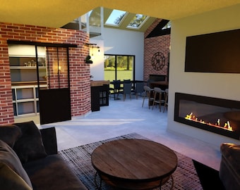 May include: A modern living room with a brick wall, a fireplace, a large TV, and a couch. The room is decorated with a rustic style, with a wooden coffee table and a rug.
