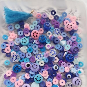 May include: A collection of colorful plastic beads in various shapes, including circles, smiley faces, and evil eyes. The beads are in shades of blue, purple, pink, and white.