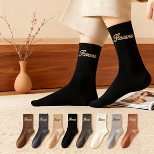 Peut inclure: Chaussettes de sport noires avec le mot "Kovans" brodé en fil doré. En dessous, une sélection de chaussettes de différentes couleurs, dont marron, gris, beige et noir, sont présentées. Les chaussettes sont en matière côtelée et douce.