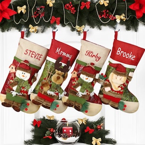 Può includere: Quattro calze di Natale personalizzate in feltro rosso e verde, ciascuna con un personaggio diverso: un pupazzo di neve, una renna, un pupazzo di neve e Babbo Natale. Le calze sono appese a una ghirlanda di rami sempreverdi con bacche rosse e ornamenti dorati. Le calze sono etichettate "Stevie", "Mommy", "Kirby" e "Brooke".