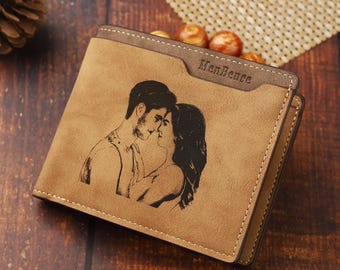 May include: A tan bi-fold wallet with a black engraved image of a couple kissing. The wallet has a brown trim and the text "MenBense" is visible on the top. The wallet is made of a suede-like material.