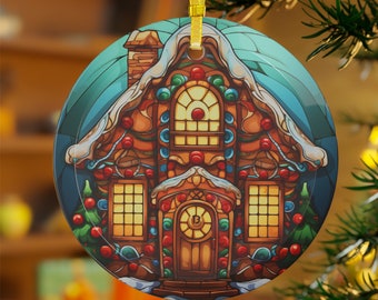Könnte beinhalten: Runder Weihnachtsschmuck mit einer farbenfrohen Illustration eines Lebkuchenhauses mit schneebedecktem Dach und festlichen Dekorationen. Der Anhänger hat ein goldenes Band zum Aufhängen und ist vor einem verschwommenen Hintergrund platziert.