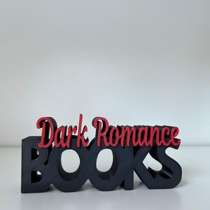 May include: A black wooden "BOOKS" sign with the words "Dark Romance" in red script. The sign is a decorative item, likely for a bookshelf or desk, and is set against a white background.