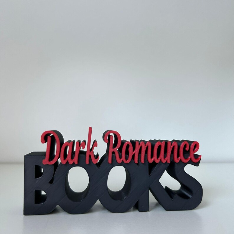 May include: A black wooden "BOOKS" sign with the words "Dark Romance" in red script. The sign is a decorative item, likely for a bookshelf or desk, and is set against a white background.