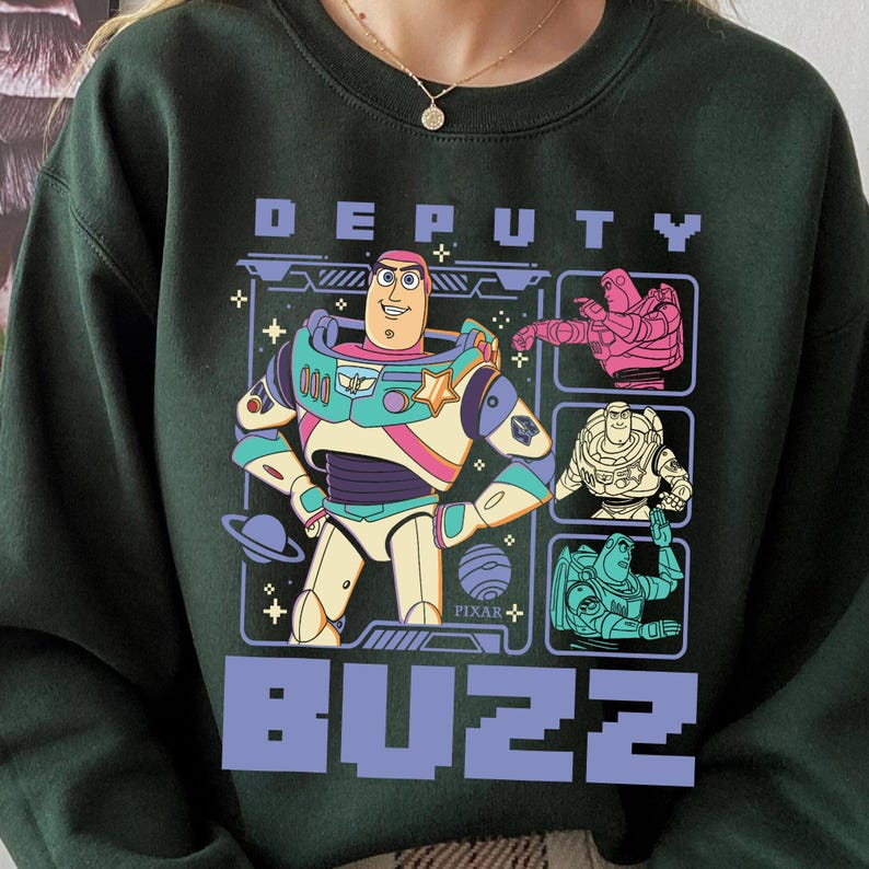 May include: Dark green sweatshirt featuring a graphic of Buzz Lightyear from Toy Story. The design includes the word "DEPUTY" above and "BUZZ" below the character. The Buzz Lightyear graphic is in a colorful, cartoon style.