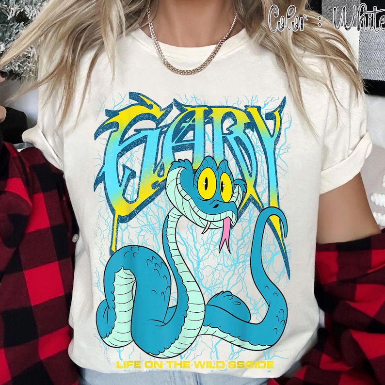Op de afbeelding: Cr&egrave;mekleurig T-shirt met een cartoon slangenontwerp. Het woord "GARY" staat in blauw en geel, met een blauwe slang met gele ogen en een roze tong. De tekst "LIFE ON THE WILD SSIDE" staat onderaan het shirt.