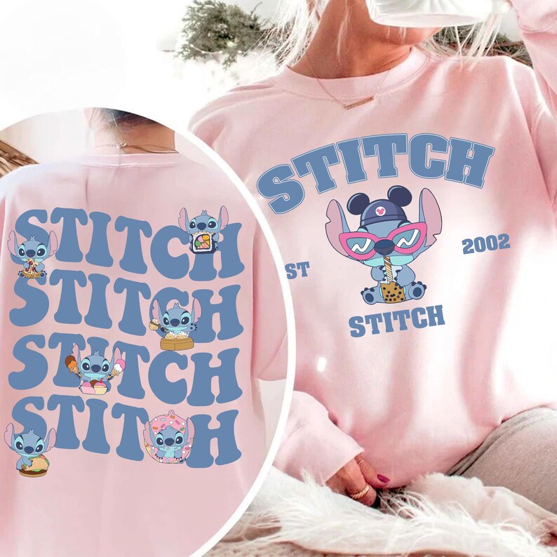 May include: A light pink sweatshirt featuring the word "STITCH" in blue block letters. The front of the sweatshirt has a graphic of the character Stitch wearing sunglasses and drinking a beverage. The back of the sweatshirt has multiple Stitch graphics.