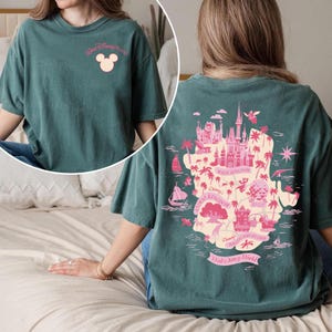 May include: Teal t-shirt with a pink graphic of the Walt Disney World map on the back. The front of the shirt has the words "Walt Disney World" and a Mickey Mouse head. The shirt is a relaxed fit.