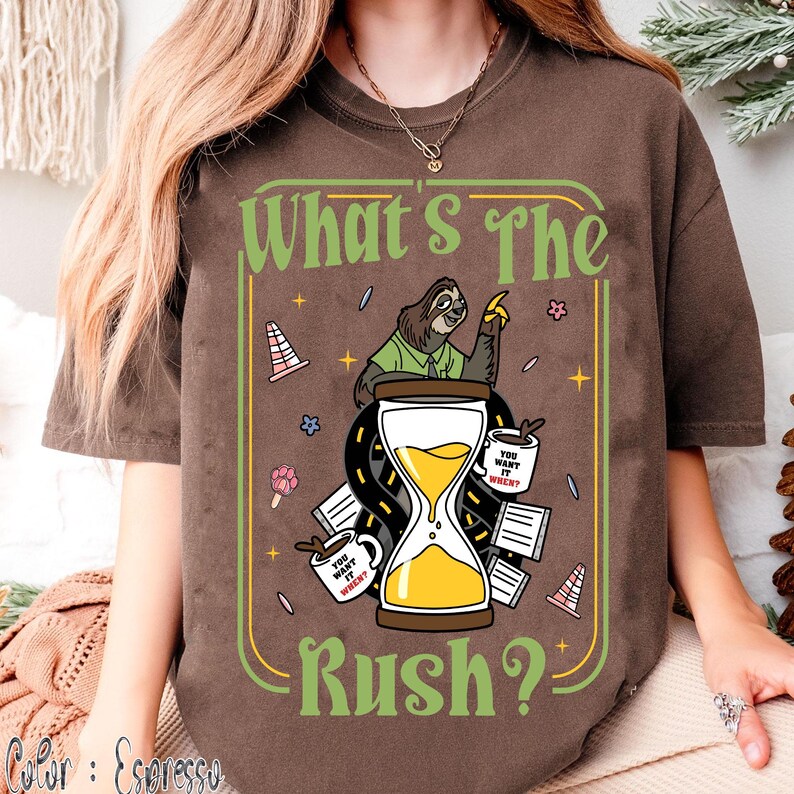 Puede incluir: Camiseta color espresso con un dise&ntilde;o que presenta un perezoso, un reloj de arena y el texto "What's The Rush?". El dise&ntilde;o incluye tazas de caf&eacute; y elementos de carretera, creando un tema relajado. La camiseta es c&oacute;moda y casual.